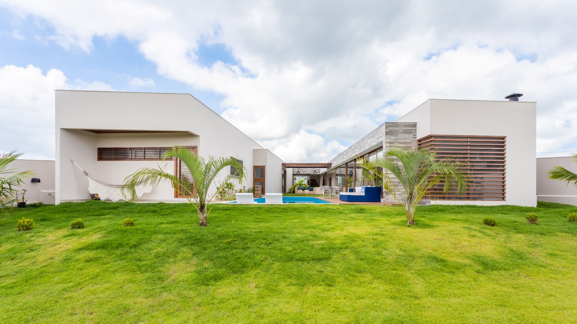 À direita, o volume das áreas comuns, à esquerda, o volume das áreas privativas. A prainha da piscina e o deck se conectam ao grande jardim, criando uma relação agradável entre interior e exterior. Ambos adquirem uma forma reta em referência às linhas ortogonais dos volumes da casa.