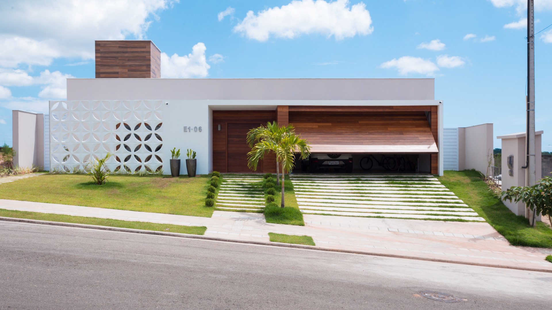 A fachada da casa possui linha retas, limpas e contemporâneas. A entrada é marcada pelo pórtico
branco e de madeira, que se contrapõe à leveza do cobogó cerâmico branco que resguarda o ambiente
do escritório do sol poente.