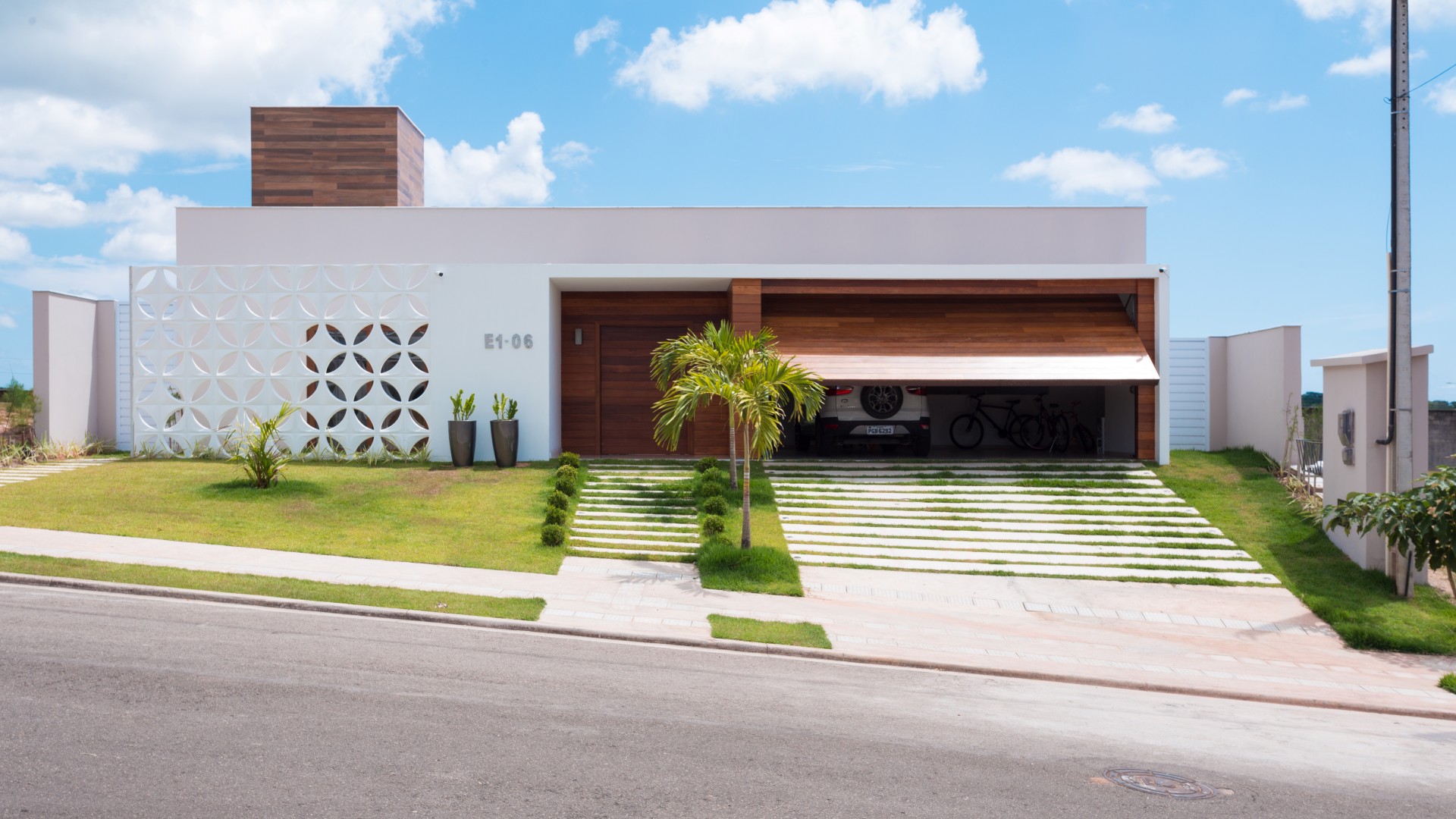 A fachada da casa possui linha retas, limpas e contemporâneas. A entrada é marcada pelo pórtico
branco e de madeira, que se contrapõe à leveza do cobogó cerâmico branco que resguarda o ambiente
do escritório do sol poente.